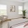 Three-Bedroom Homes for Rent in Belton, MO - Elm Grove - Bedroom with Luxury Vinyl Plank Flooring, Area Rug, Large Bed, Corner Chair, Side Table, and Windows.
