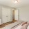 a room with white walls and a wood floor with a white couch and a painting on the wall